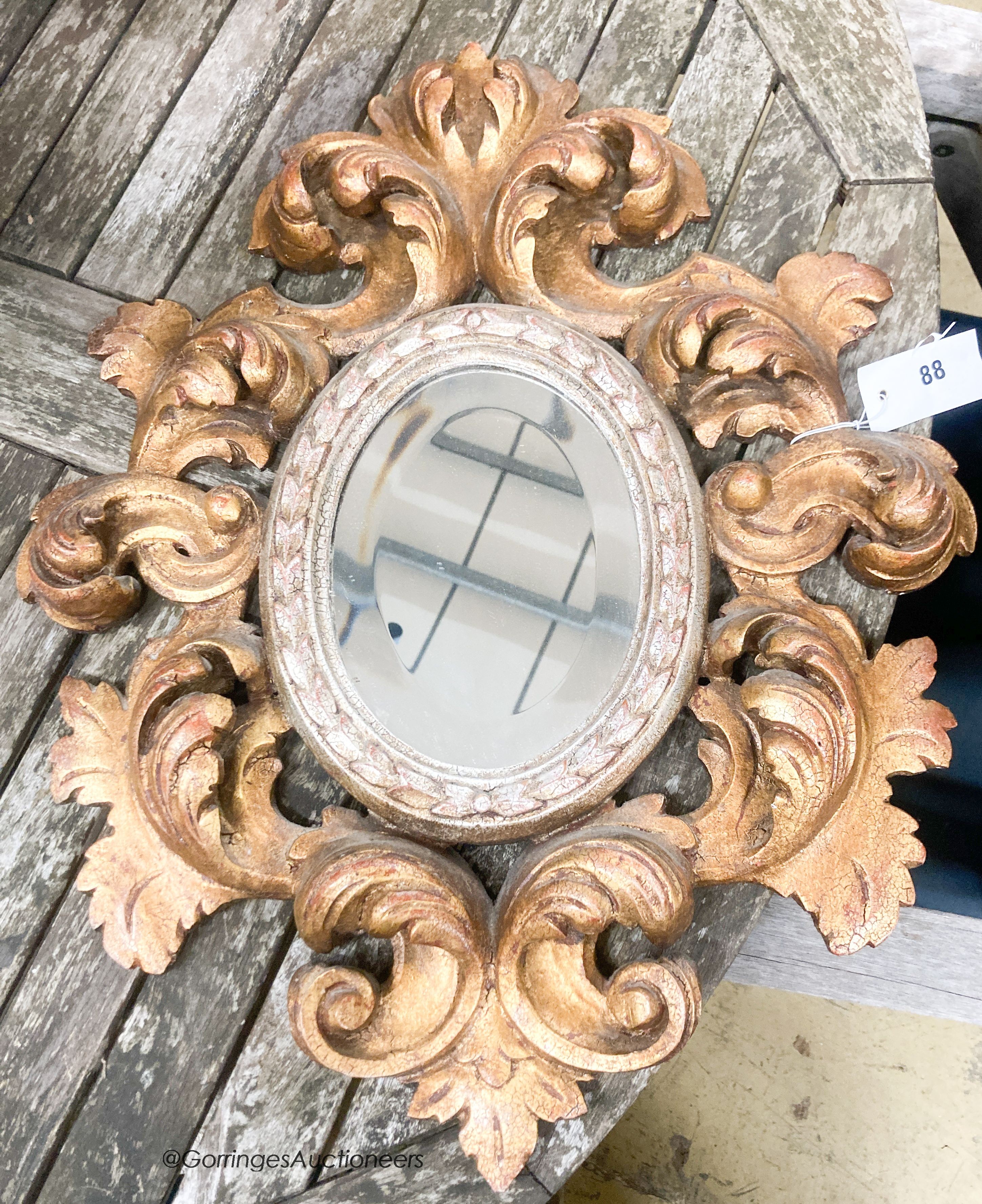 A 1930's Italian carved giltwood oval mirror, width 47cm, height 59cm